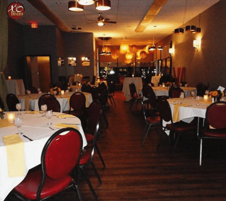 This picture shows the function room at XO Bistro and is full of white tablecloth tables with red chairs. The function room in Manchester, NH is ready to host guests for the night.